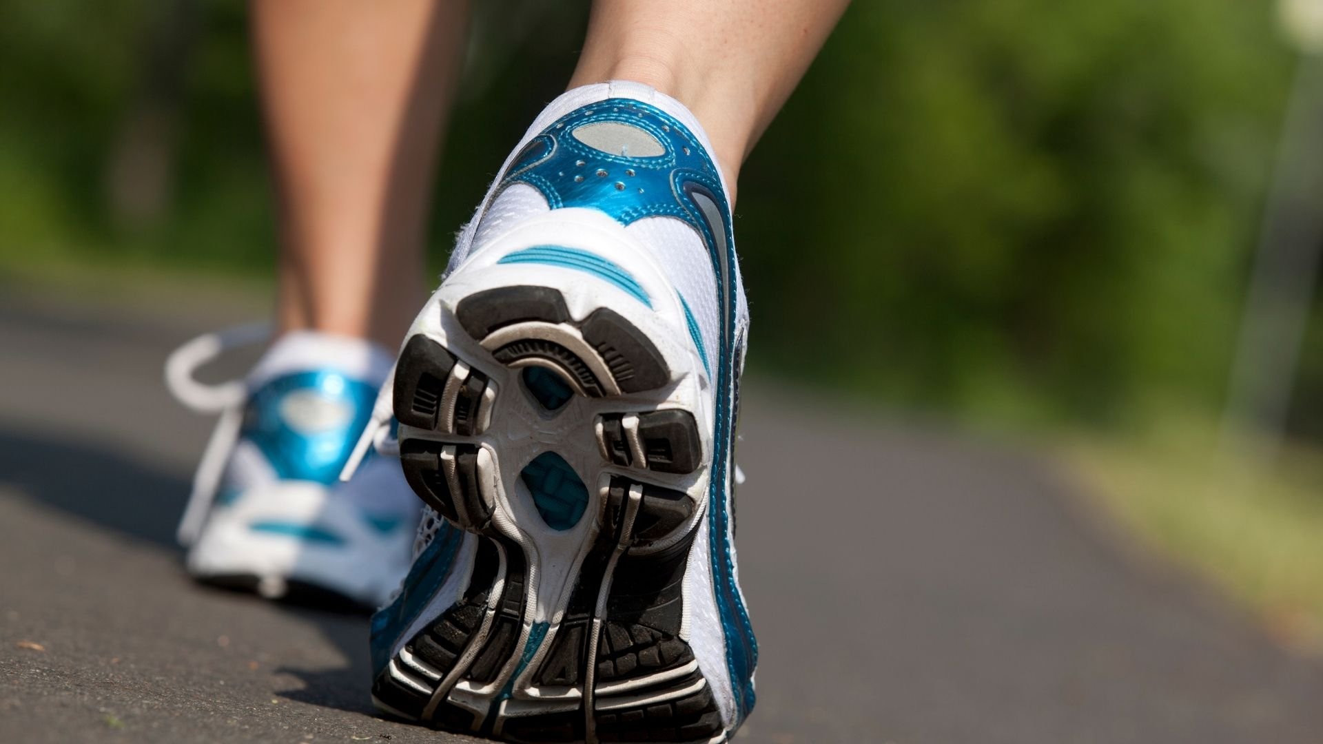 Close-up of blue and white running shoe sole during outdoor jogging activity.