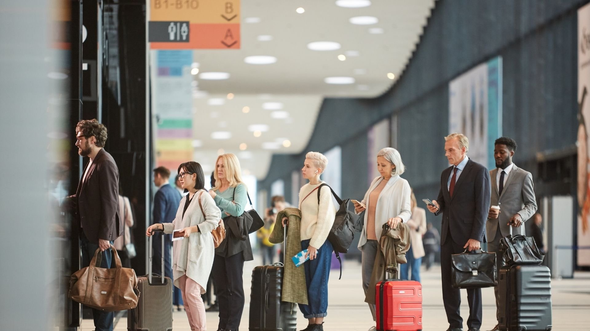Diverse travelers walking through modern airport terminal with luggage and carry-on bags