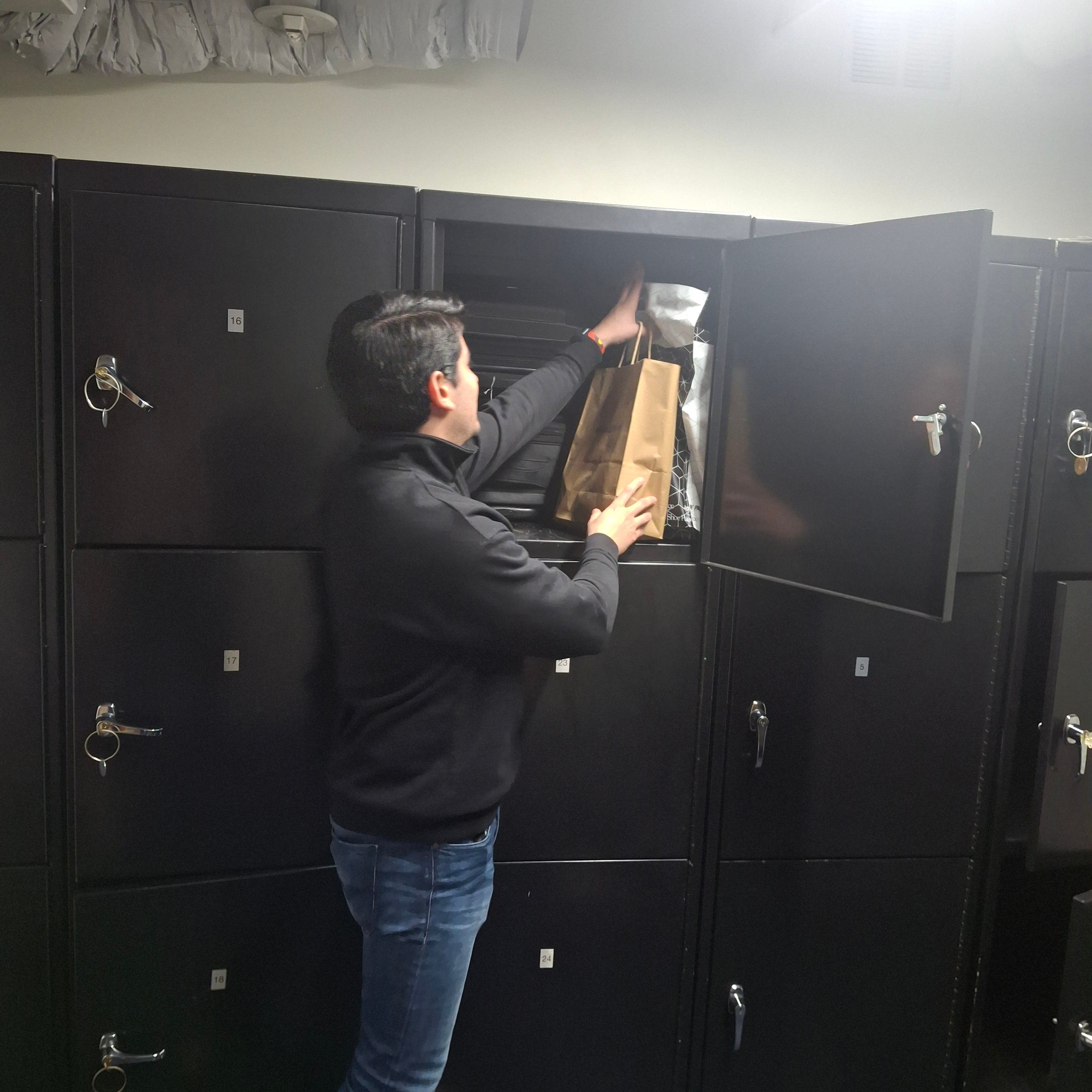 Man retrieving package from metal mailbox locker wall in facility