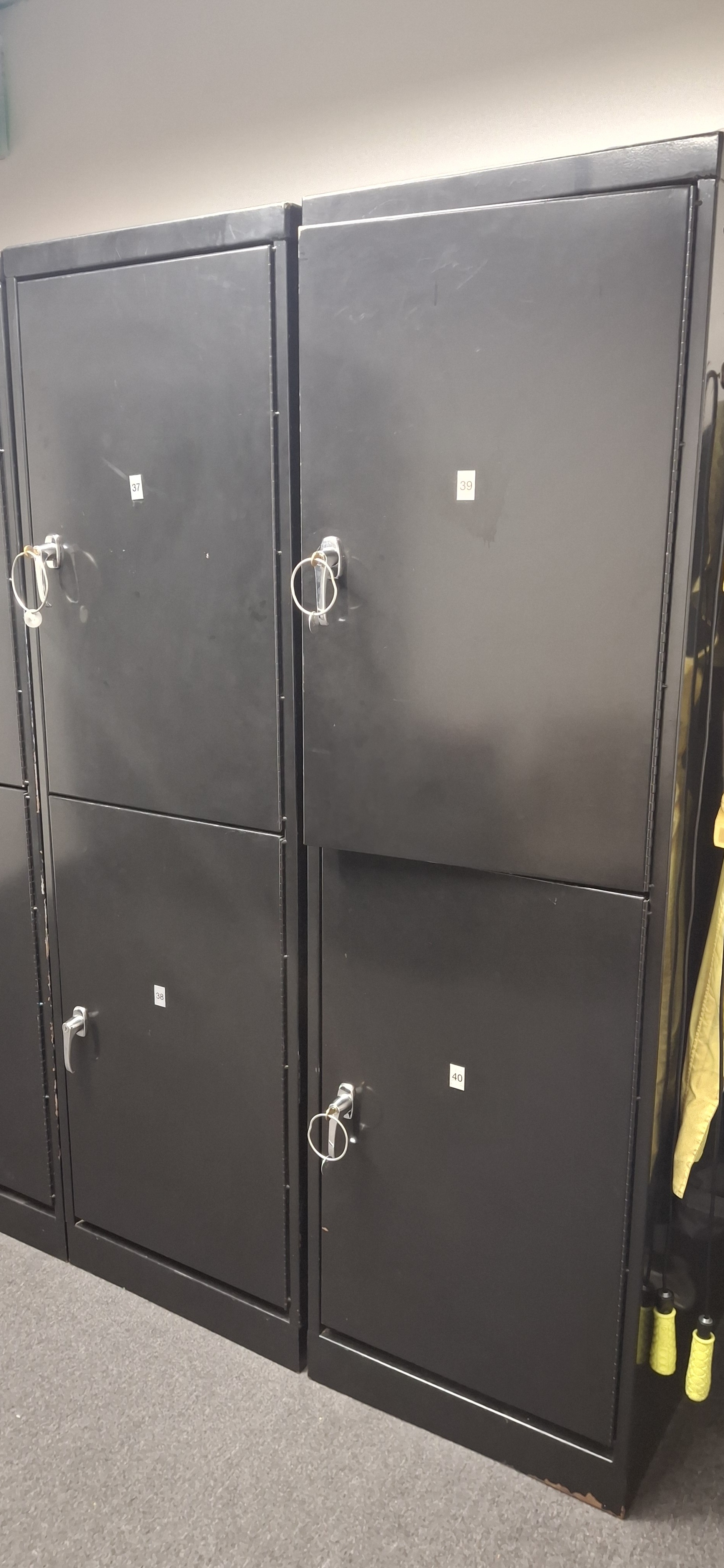 Two black metal cabinet units with circular handles and labeled compartments indoors.