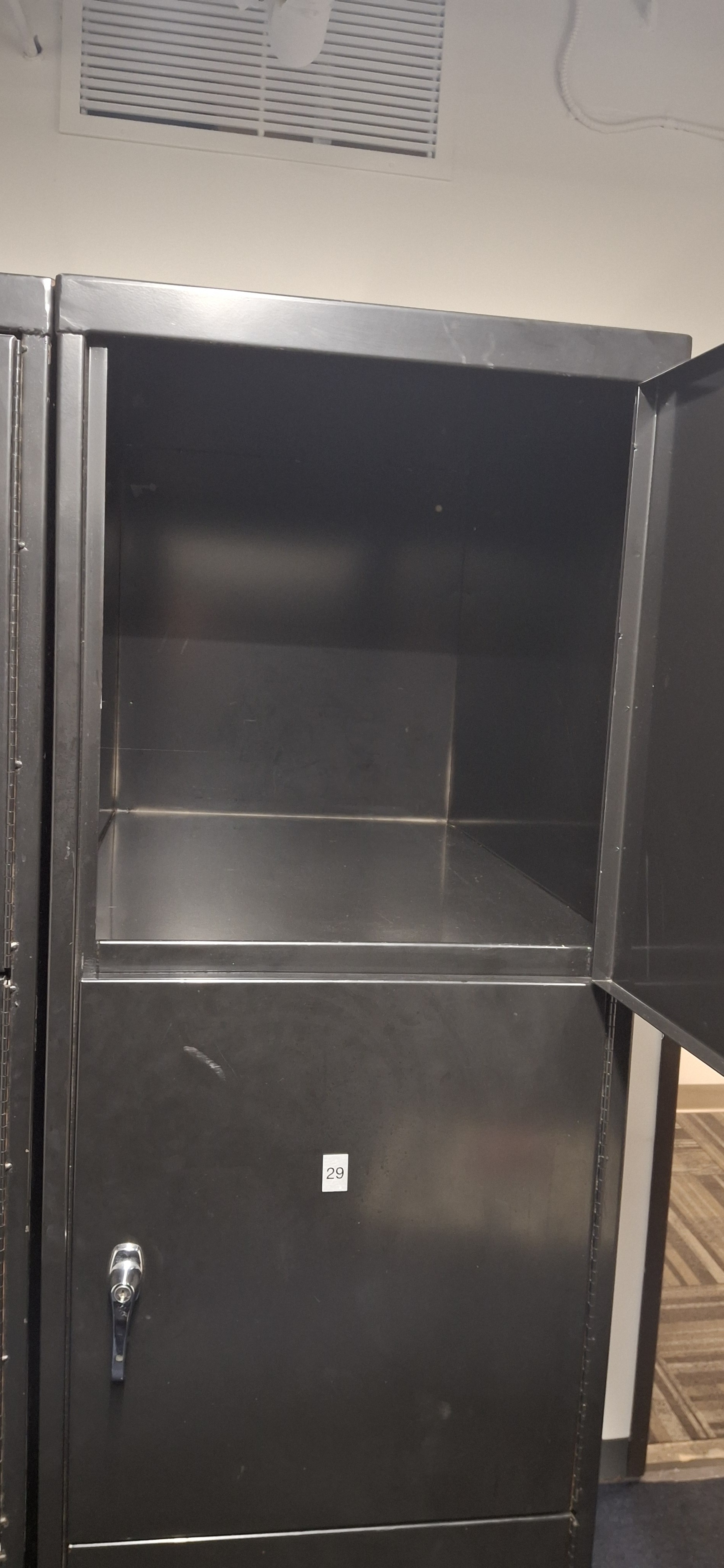 Black metal cabinet with glass shelves and numbered label "29" on lower section